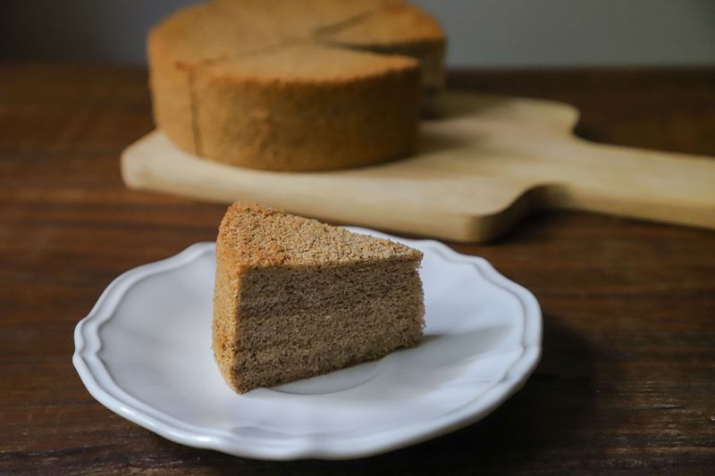 A slice of moist sponge cake on a white plate, perfect for dessert indulgence.