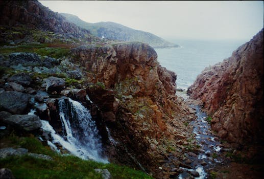 Stunning waterfall flowing through rocky cliffs into the sea at Teriberka, Russia.