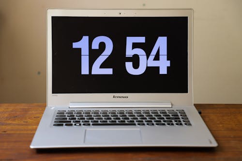 Free включенный серебристый ноутбук Lenovo показывает часы в 12:54 Stock Photo