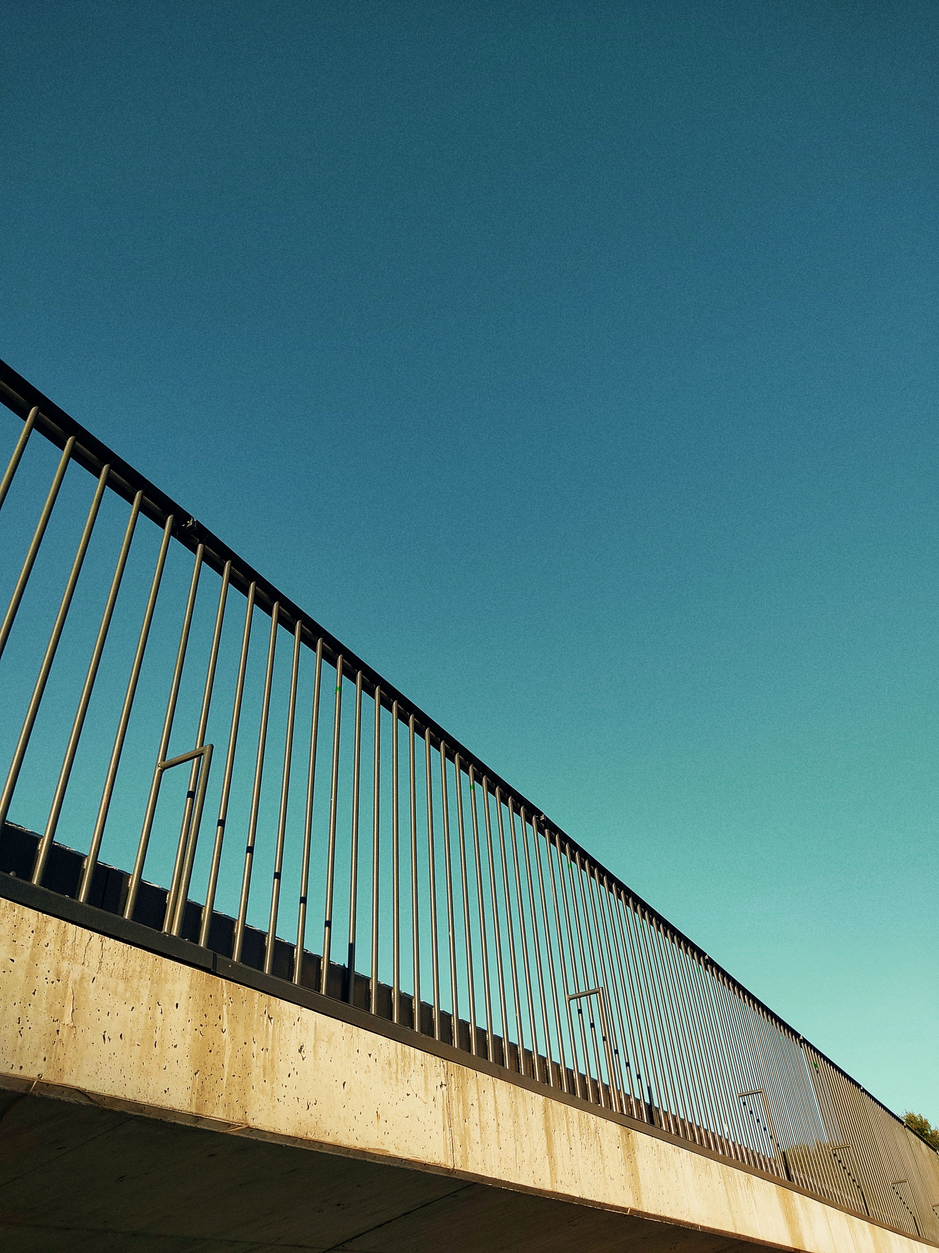 Low angle view of a modern pedestrian bridge with railings against a clear blue sky in Oliveira de Frades, Portugal.
