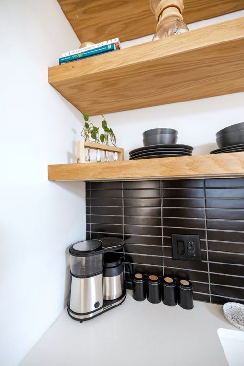 Free Stylish kitchen featuring a sleek coffee maker on a clean countertop with wooden shelves. Stock Photo