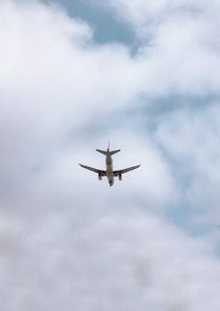 Aircraft captured from below as it flies through the clouds on a overcast day.