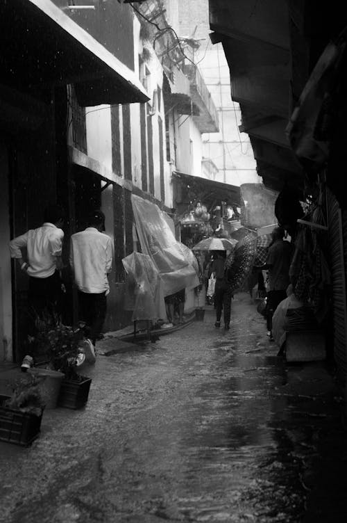 Grayscale Photo of People Walking on Alleyway