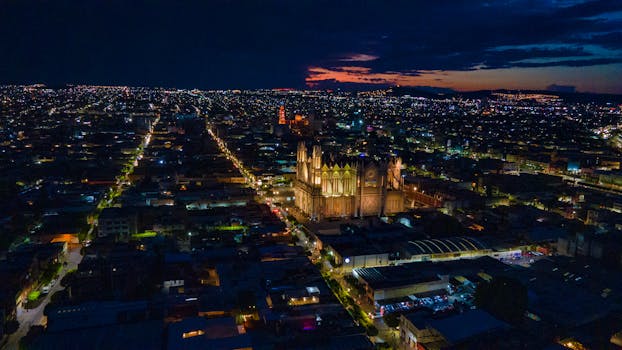 Stunning aerial view of a vibrant cityscape with illuminated buildings at night.