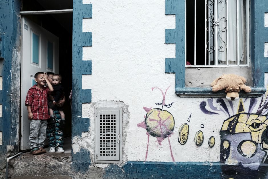 Dos niños juegan en una entrada con arte urbano en Bogotá, mostrando la vida y cultura de la ciudad.