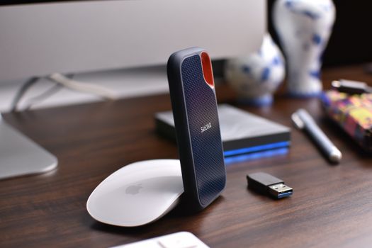 Close-up of a desk with external drive, USB stick, and computer mouse for modern office use.