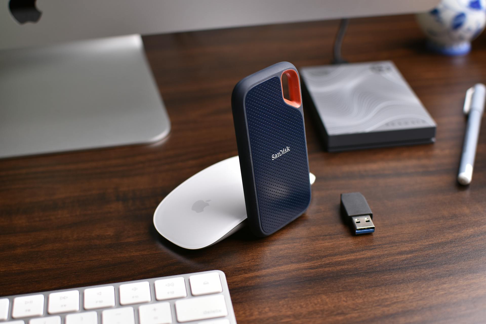 Close-up of a modern desk setup with a SanDisk external hard drive and electronics on a wooden surface.