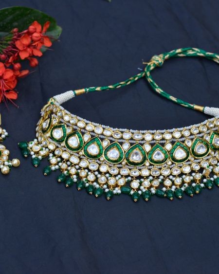 Emerald-green kundan choker with beaded tassels on a navy background