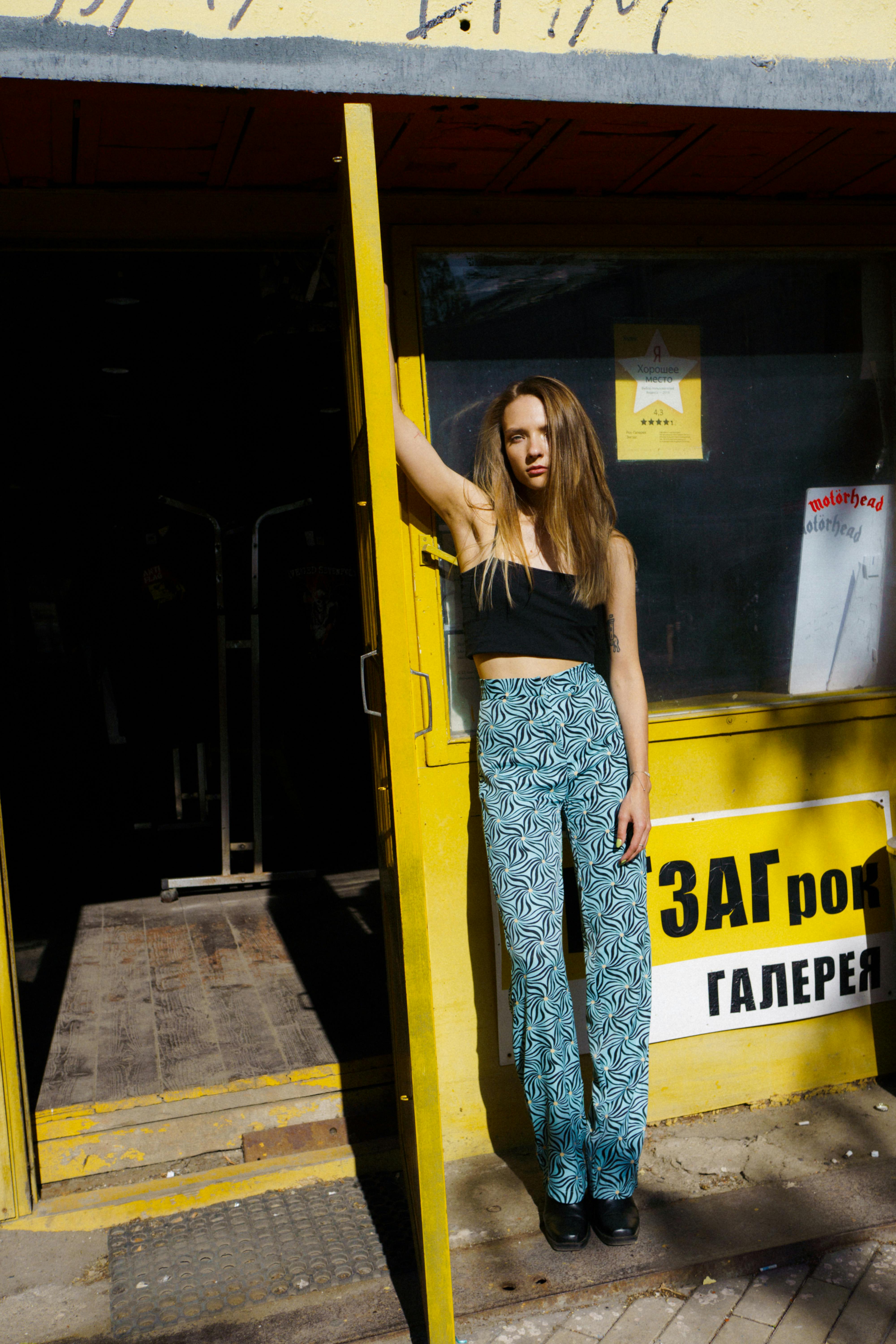 Fashionable woman posing by a vibrant yellow door in casual chic style.