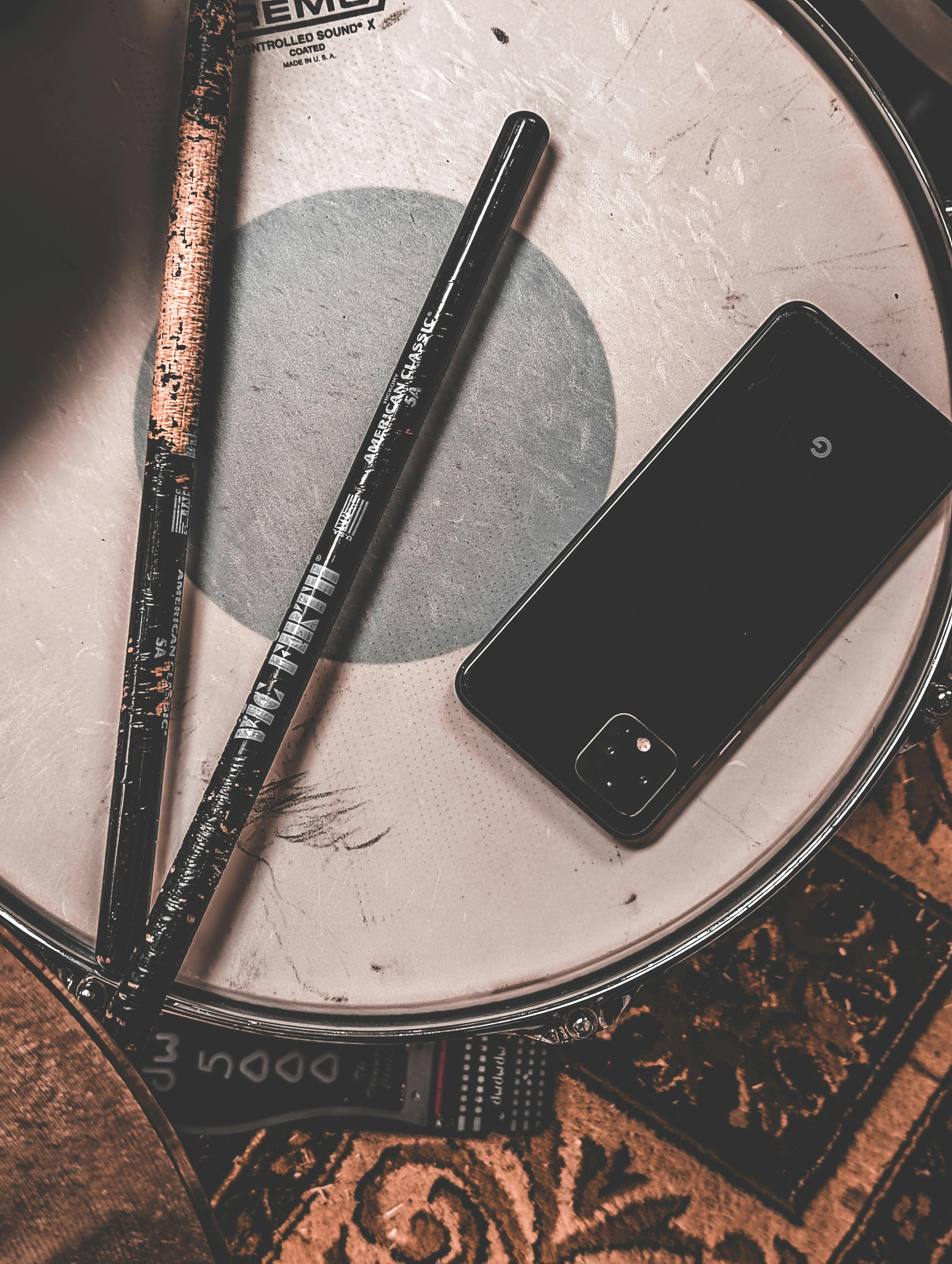 phone and drumsticks lying on a drum