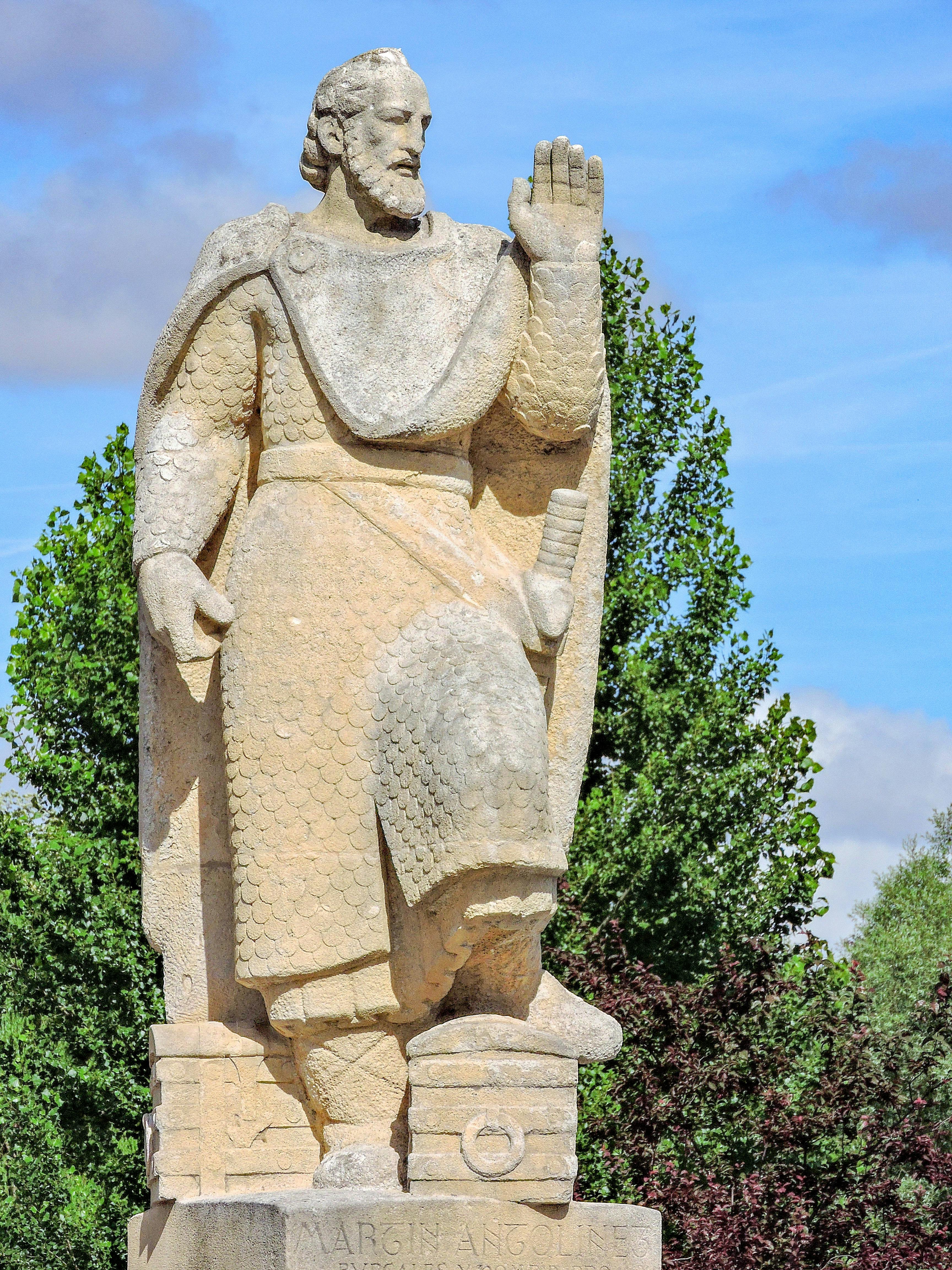 Stone statue of Martin Antolinez in Burgos, Spain under clear sky, showcasing historical artistry.