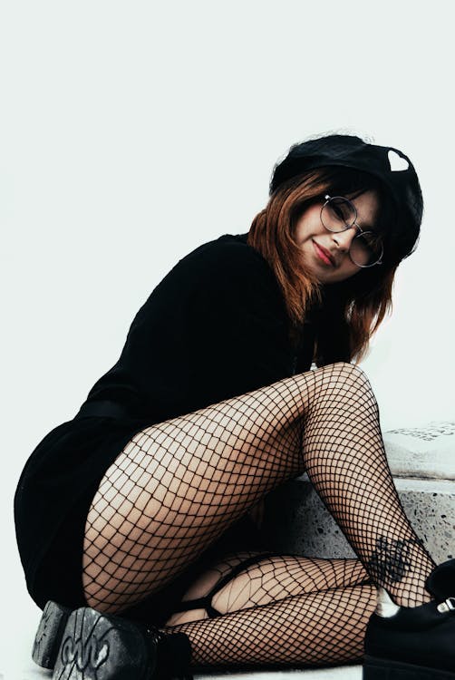 A Woman in Black Dress Wearing Fishnet Stockings Sitting Near the