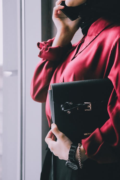 Woman in Red Long Sleeve Shirt Holding Black Leather Handbag