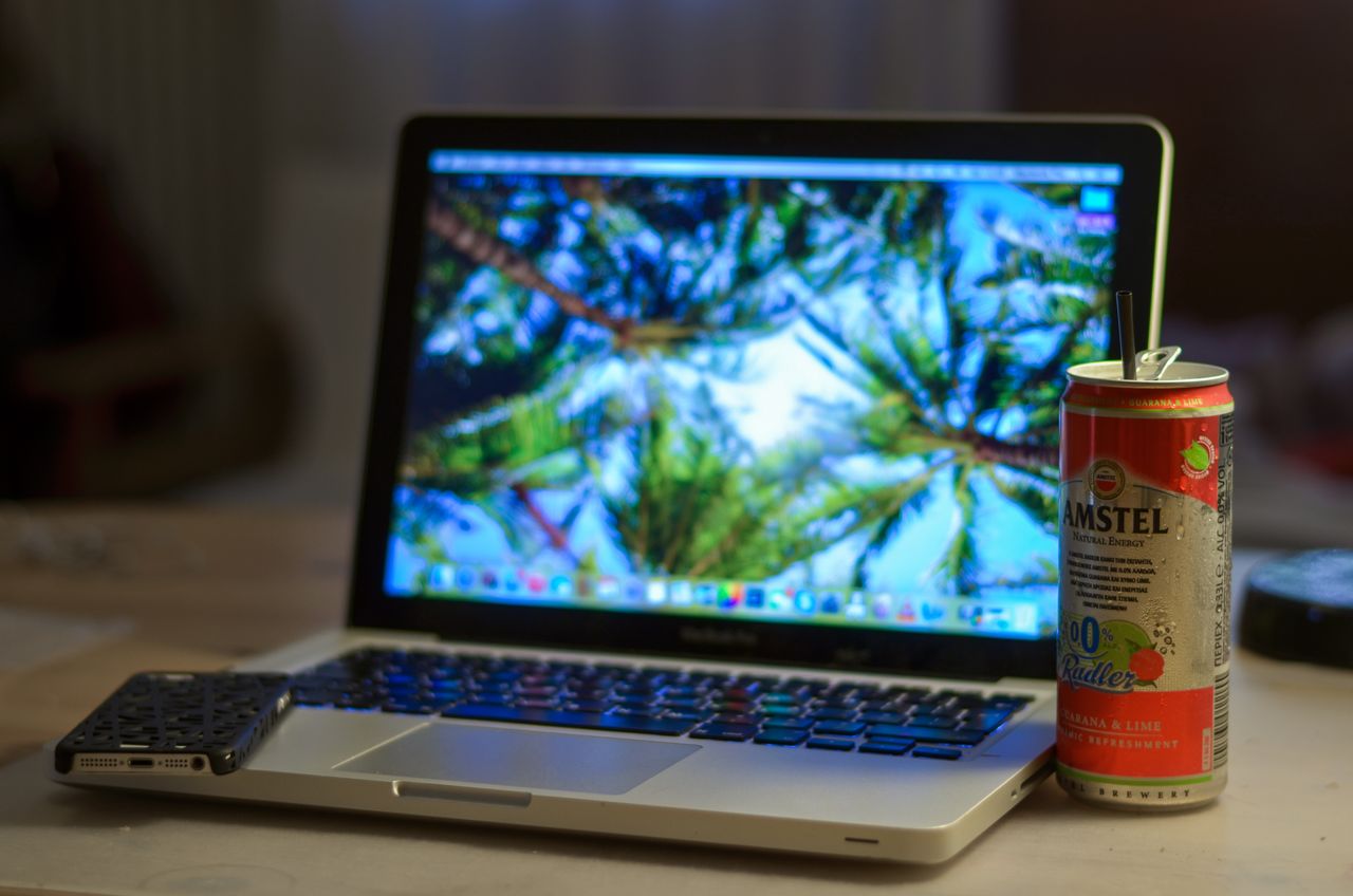 a laptop and a refreshing can of drink placed on a desk indoors