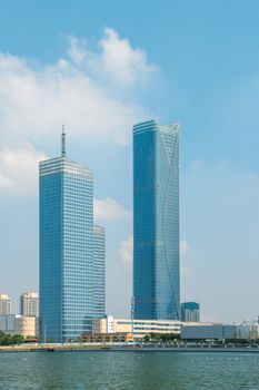 Skyline view of modern high rise skyscrapers by a waterfront under a clear blue sky.