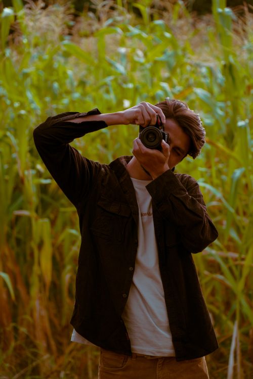 Free Photographer taking a photo in a lush cornfield, highlighting nature and creativity. Stock Photo