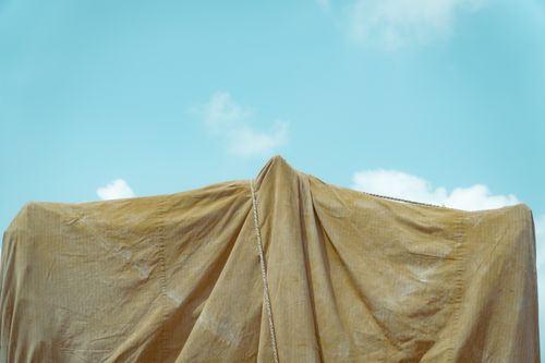 Free Yellow fabric draped outdoors with a clear blue sky background. Minimalist scene. Stock Photo