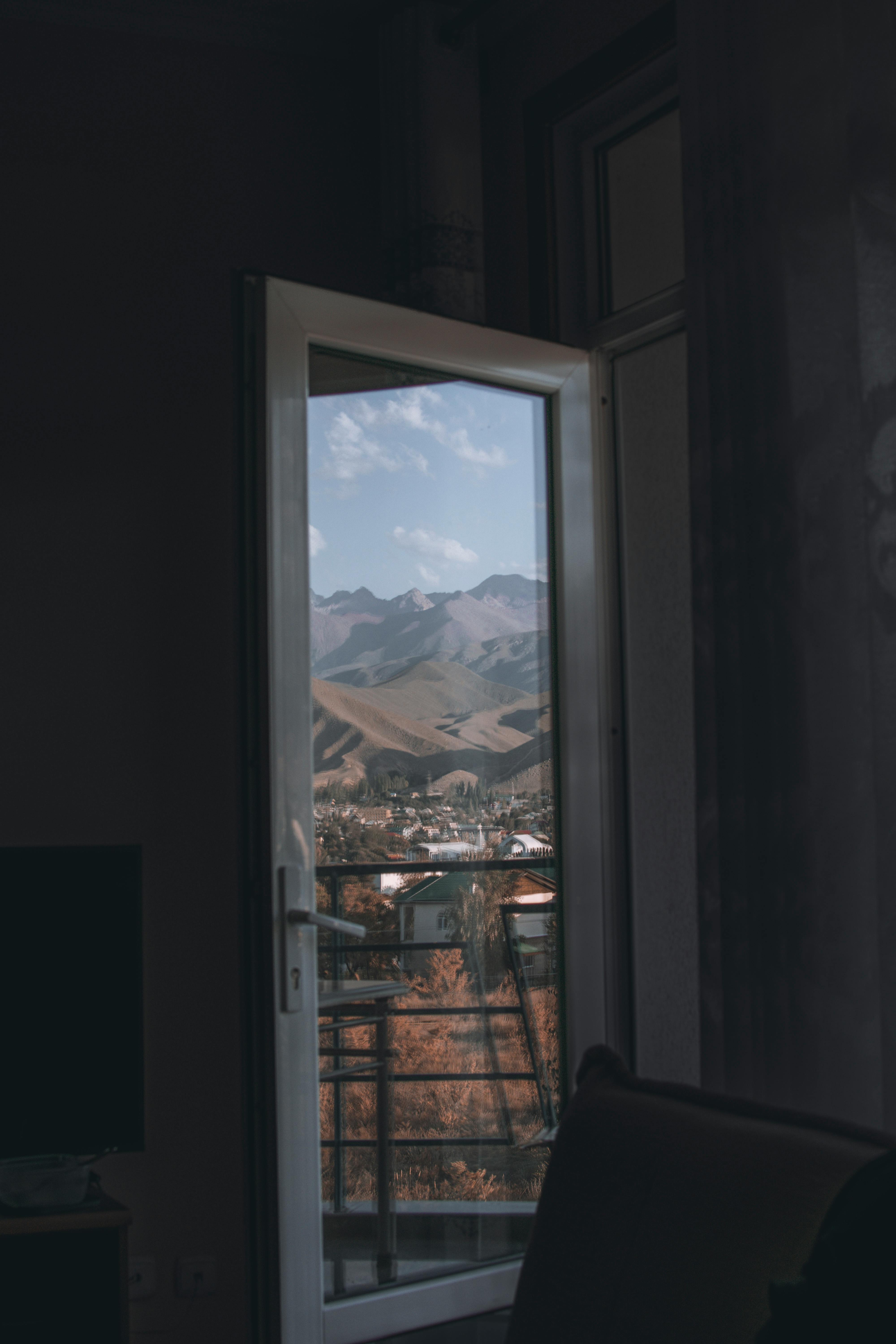 Serene mountain landscape viewed through an open indoor window, capturing natural beauty.