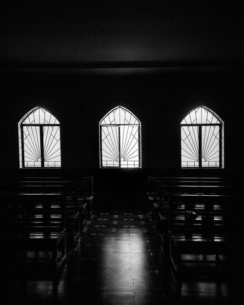 Free A captivating black and white image of a church interior featuring pointed arches and light-filled windows. Stock Photo