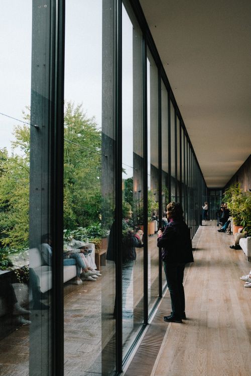 Free A contemporary indoor corridor with glass walls reflecting the spacious view and people. Stock Photo