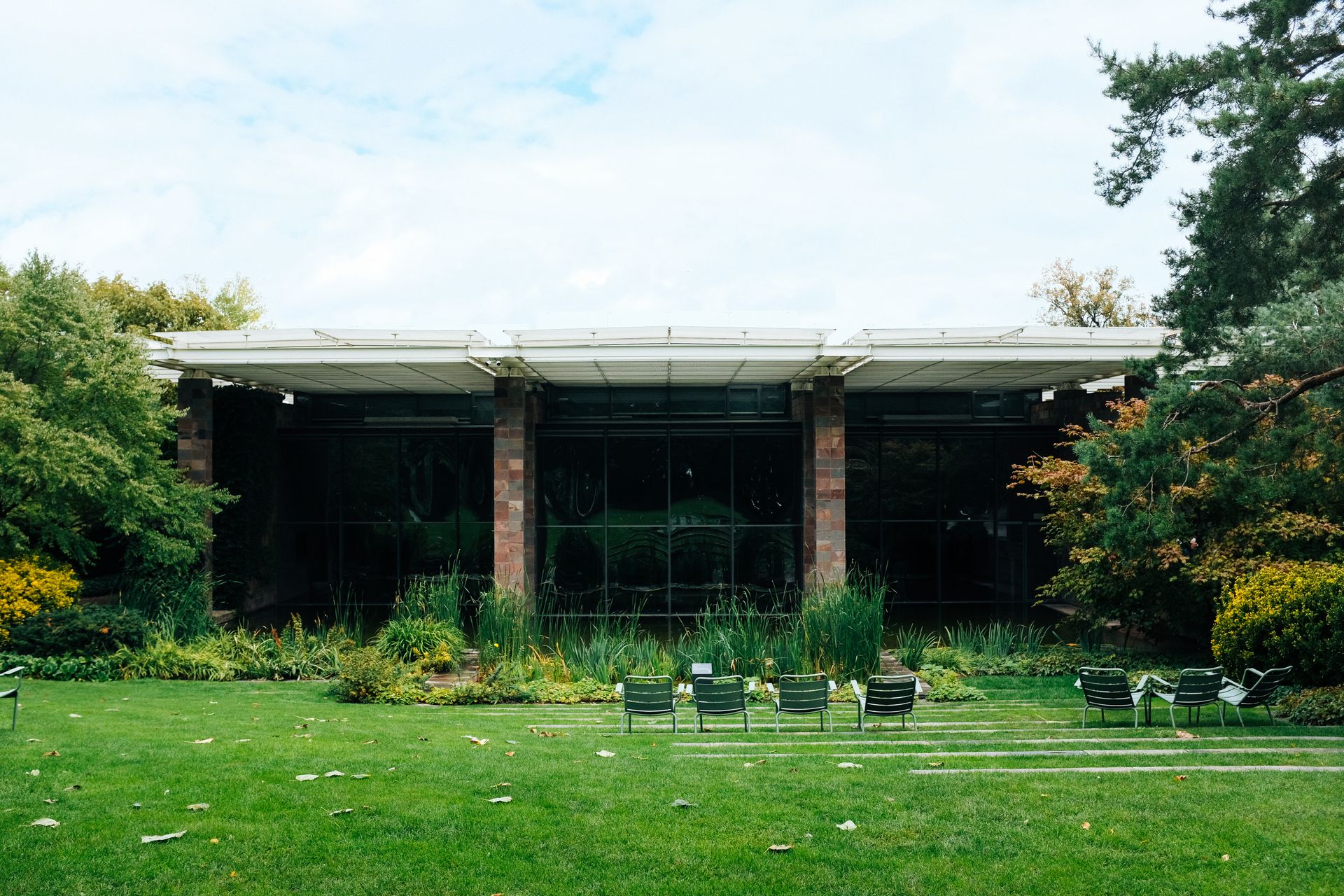 A modern house exterior with surrounding gardens and lawn chairs, ideal for outdoor relaxation.