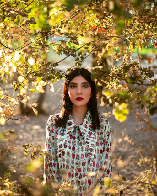 Woman in Printed Long Sleeves Standing Under the Tree Branches