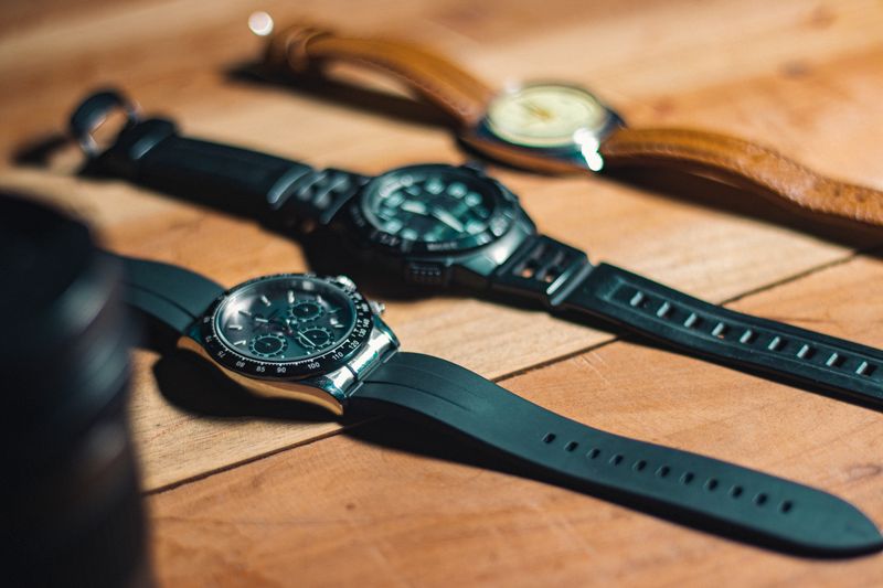 Several analog watches and spare straps laid out on wood — photo by Ranjit Pradhan on Pexels