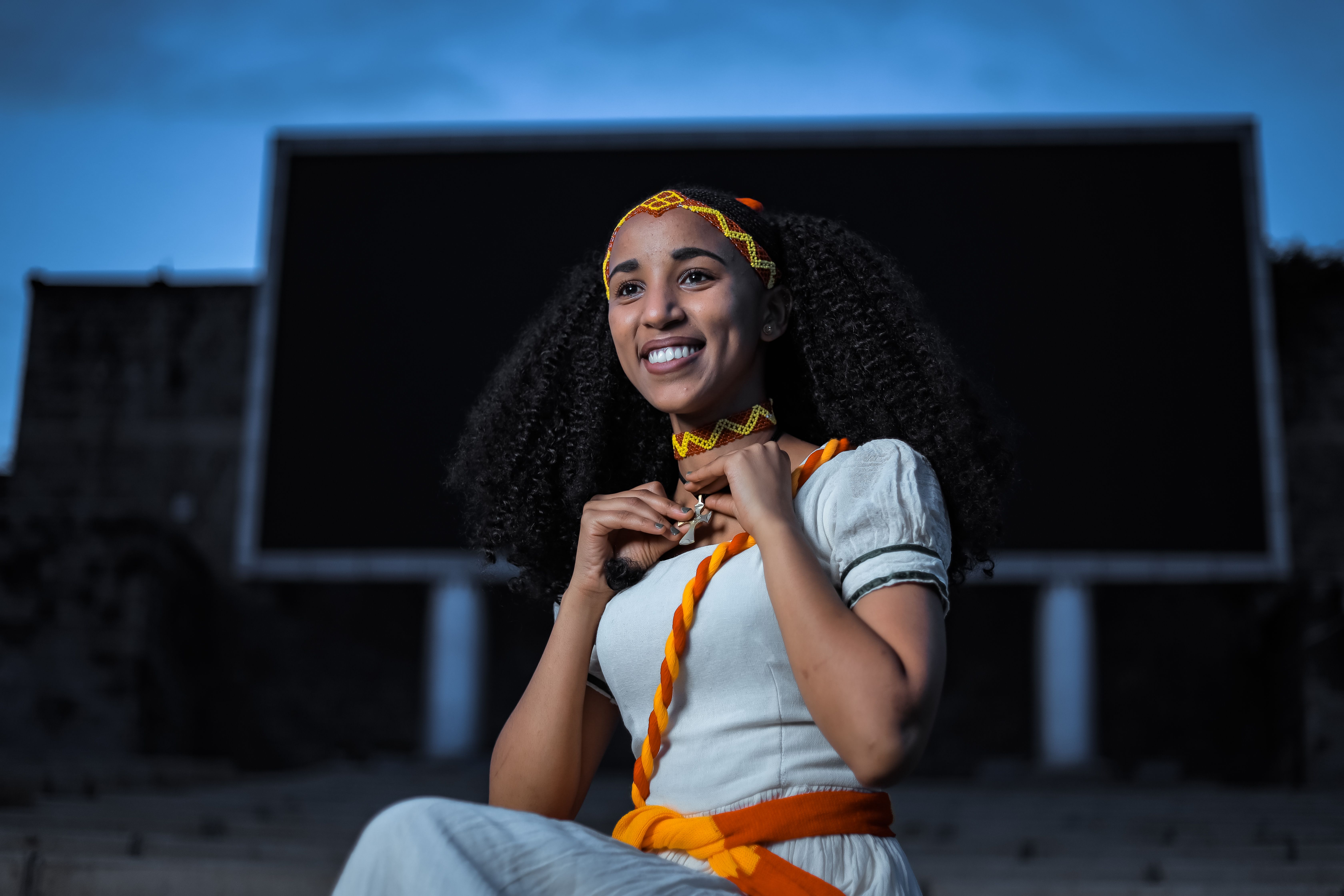 Portrait of a woman in traditional Ethiopian attire, smiling at dusk in Addis Ababa.