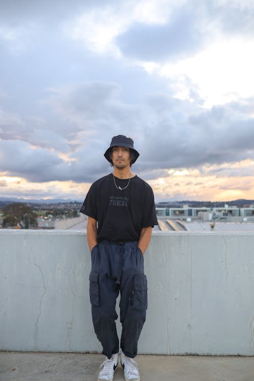 A Man in Black Shirt Standing Near the Concrete Wall