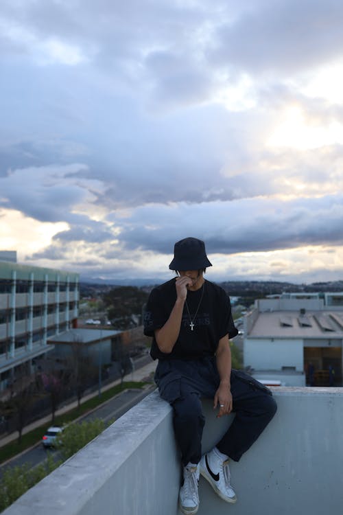 Man Sitting on Rooftop Concrete Wall