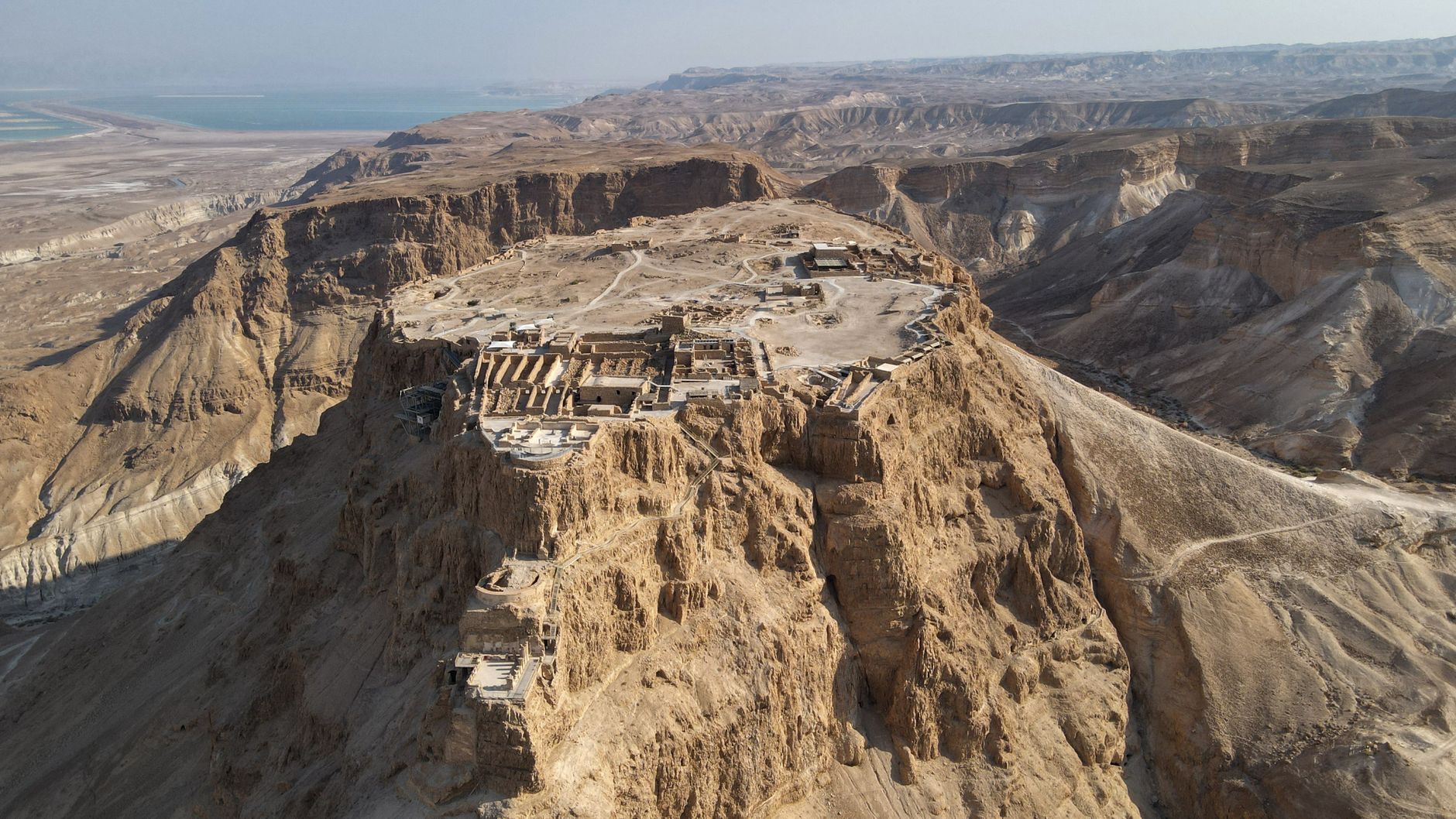 Stunning aerial shot of the ancient Masada Fortress atop a rocky plateau in Israel's desert landscape.