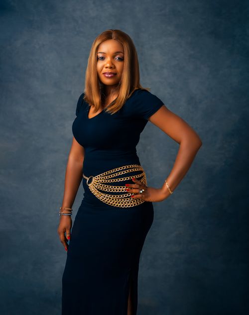 Free Stylish woman in a dark dress with chain belt posing confidently in studio setting. Stock Photo