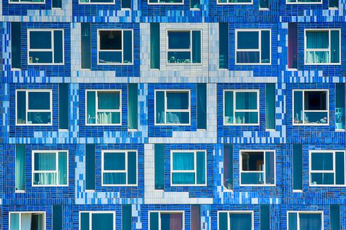 Free A modern building facade with blue and white tiles and numerous windows, creating a geometric pattern. Stock Photo