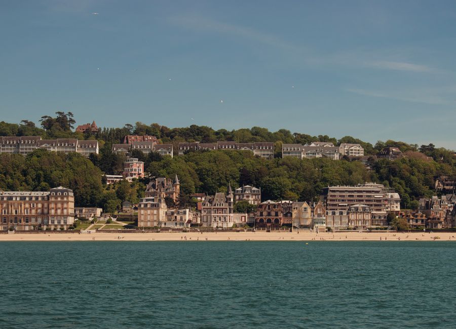 Scenic view of Trouville-sur-Mer beach and charming architecture in Normandy, France under a clear blue sky.