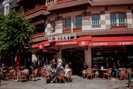 Charming street view of Le Morny's Café in Deauville with people enjoying outdoor seating.