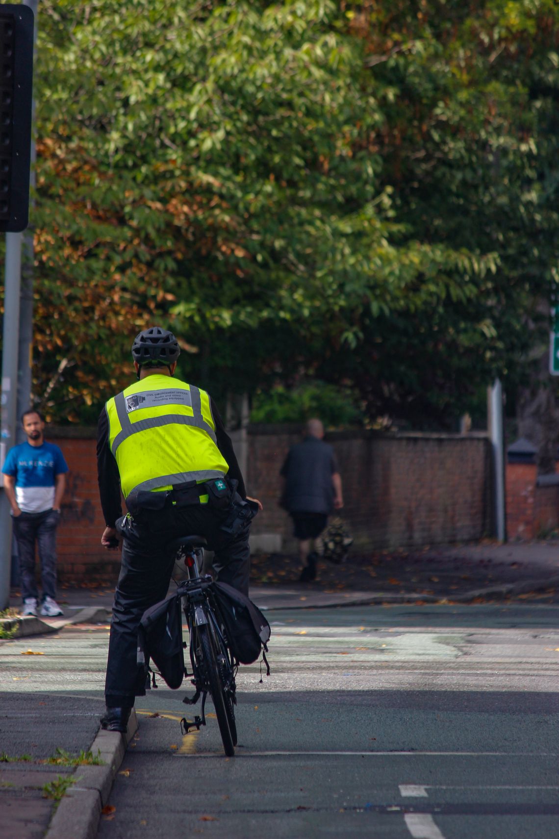 Cyclist wearing a helmet and visible safety clothing while riding on a city street
