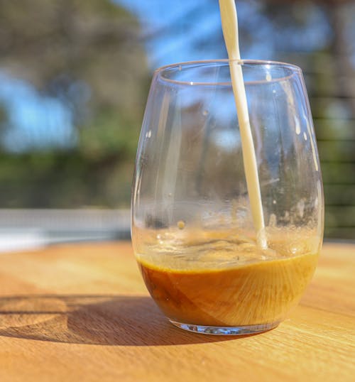 A Pouring Milk on Drinking Glass with Coffee