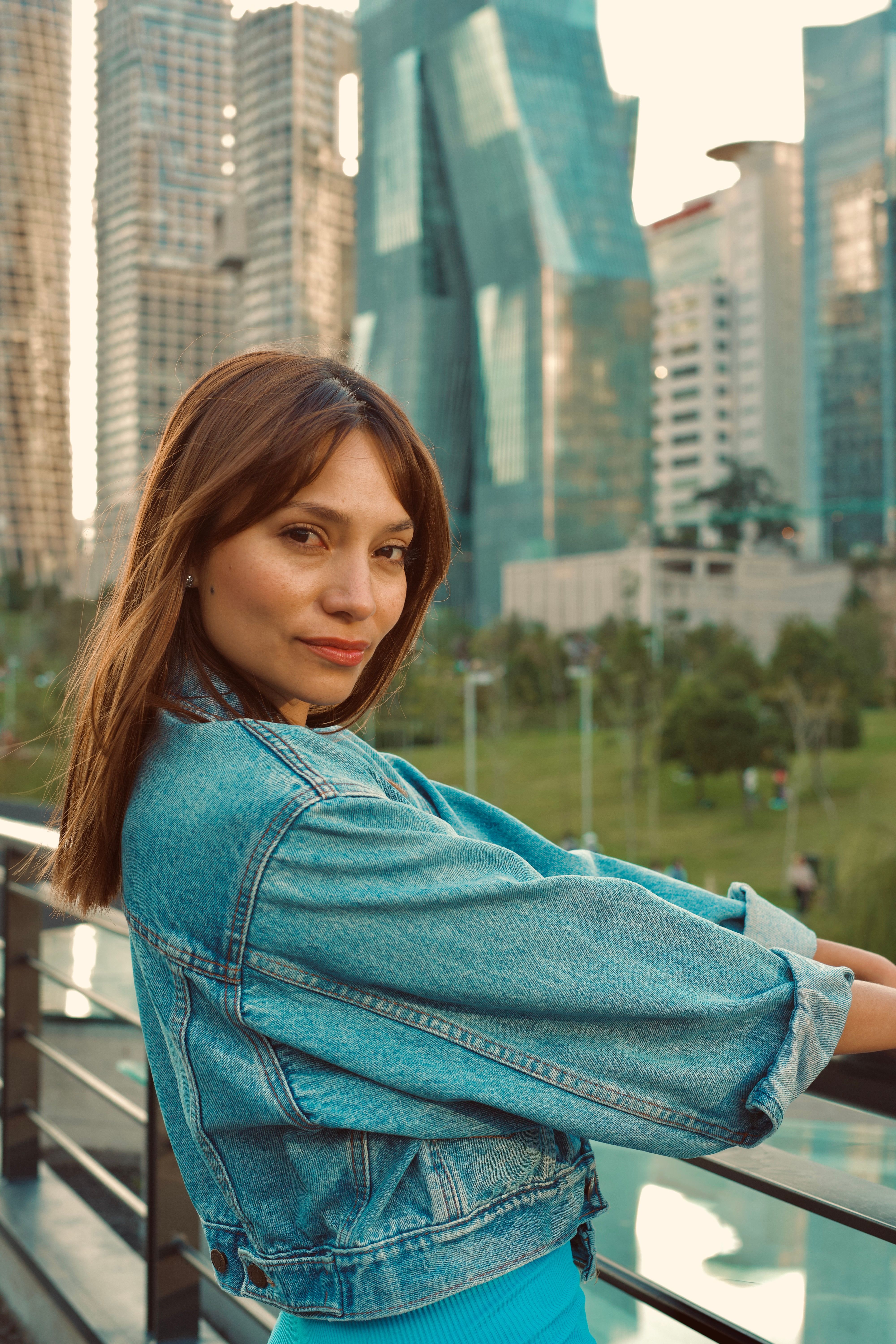Stylish woman in denim jacket posing with city skyline background in Mexico City.
