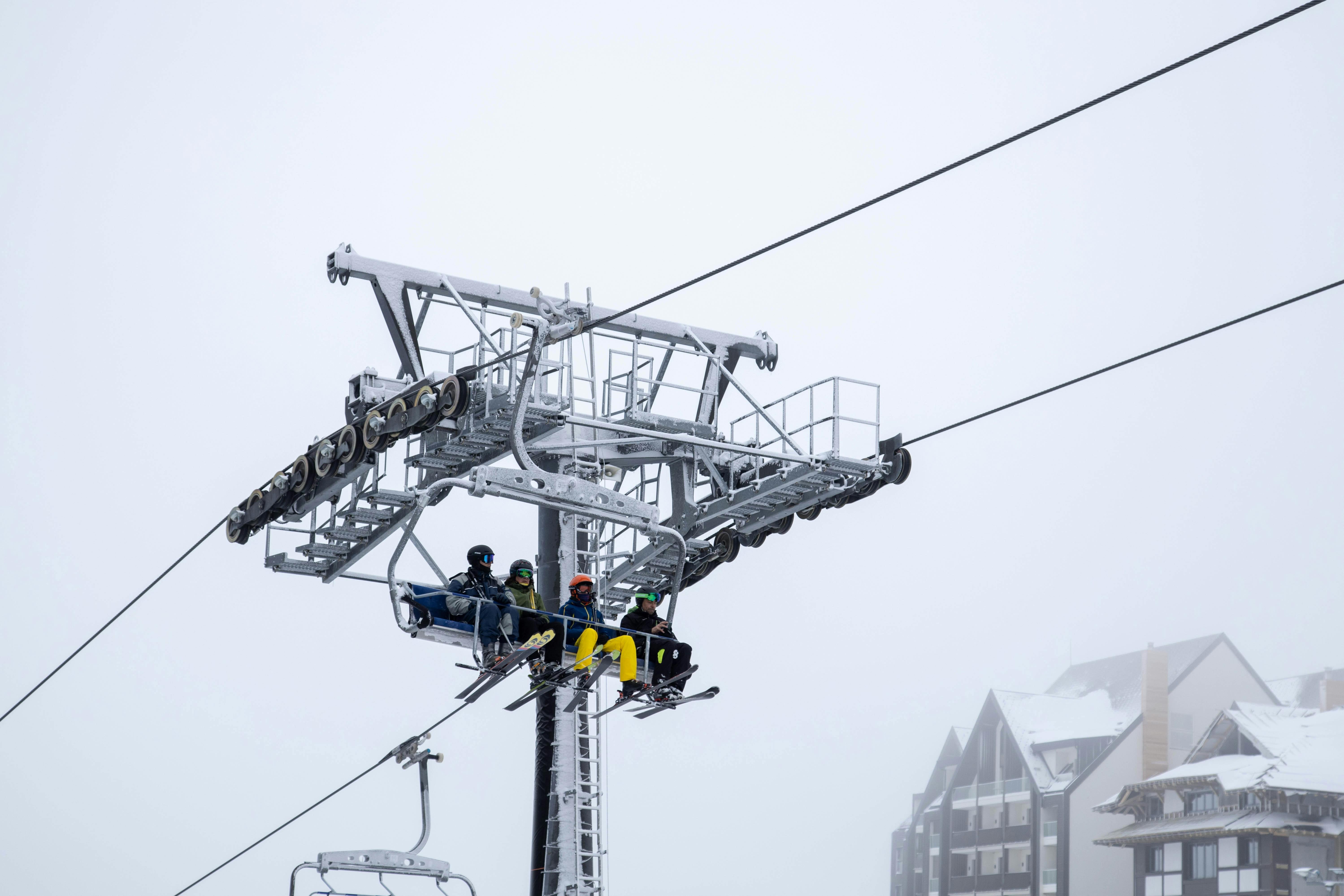 Prescription Goggle Inserts - Group of skiers sitting on a ski lift at a snowy mountain resort. Overcast winter setting.