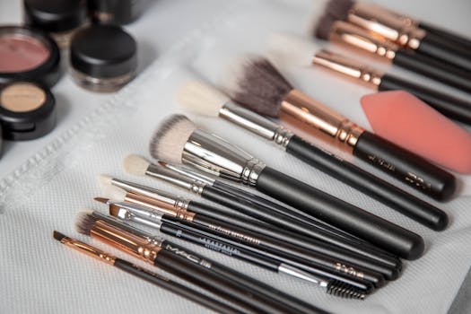 A collection of professional makeup brushes and tools arranged on a white towel with various cosmetic products.