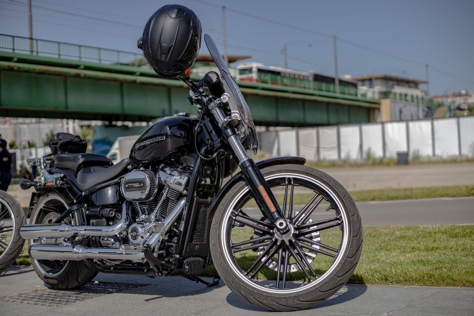 A stylish black Harley Davidson motorcycle parked outdoors with a helmet on the handlebars.