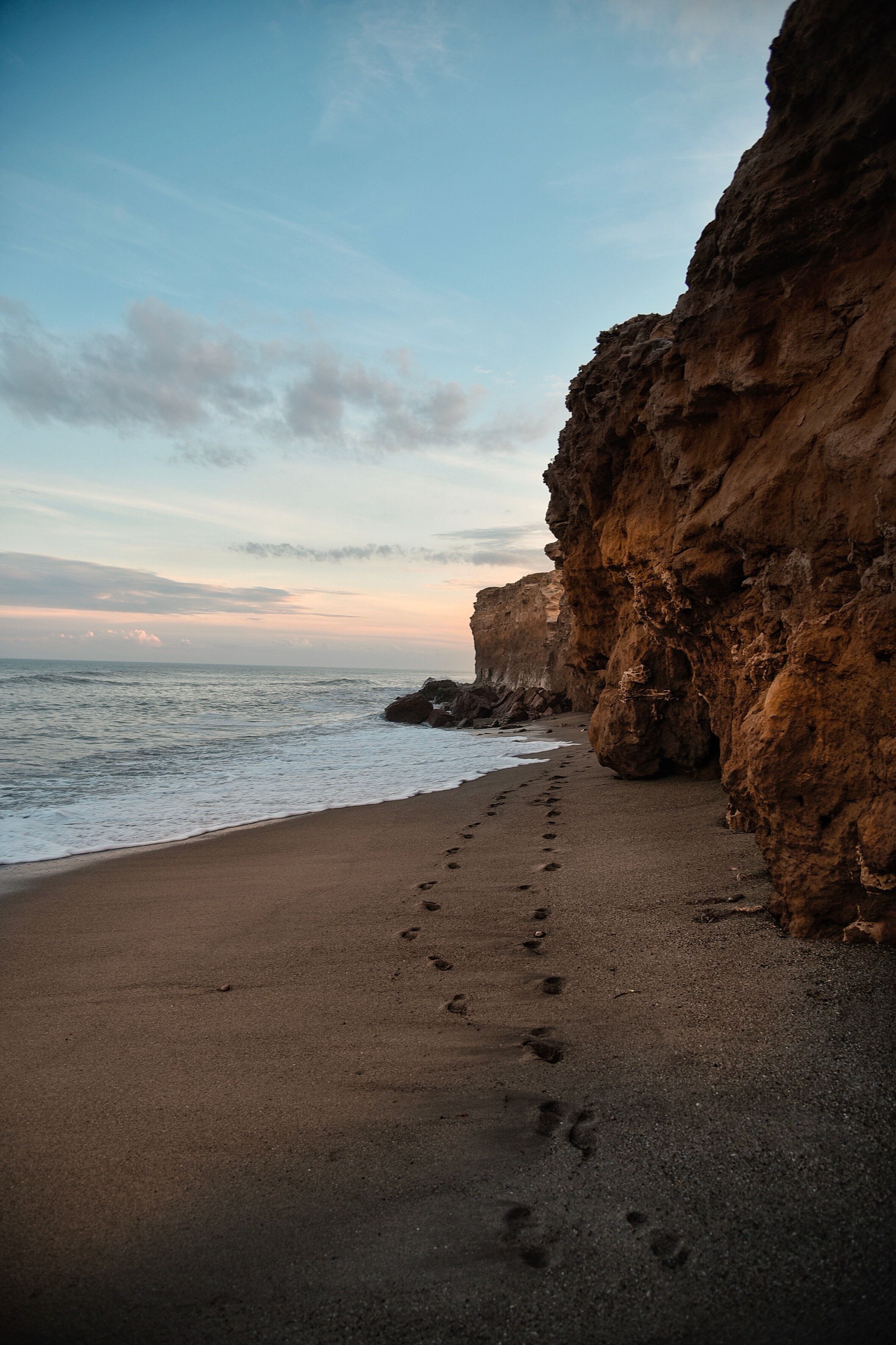 A Rock Formation on the Beach Under the Blue Sky and White Clouds ...