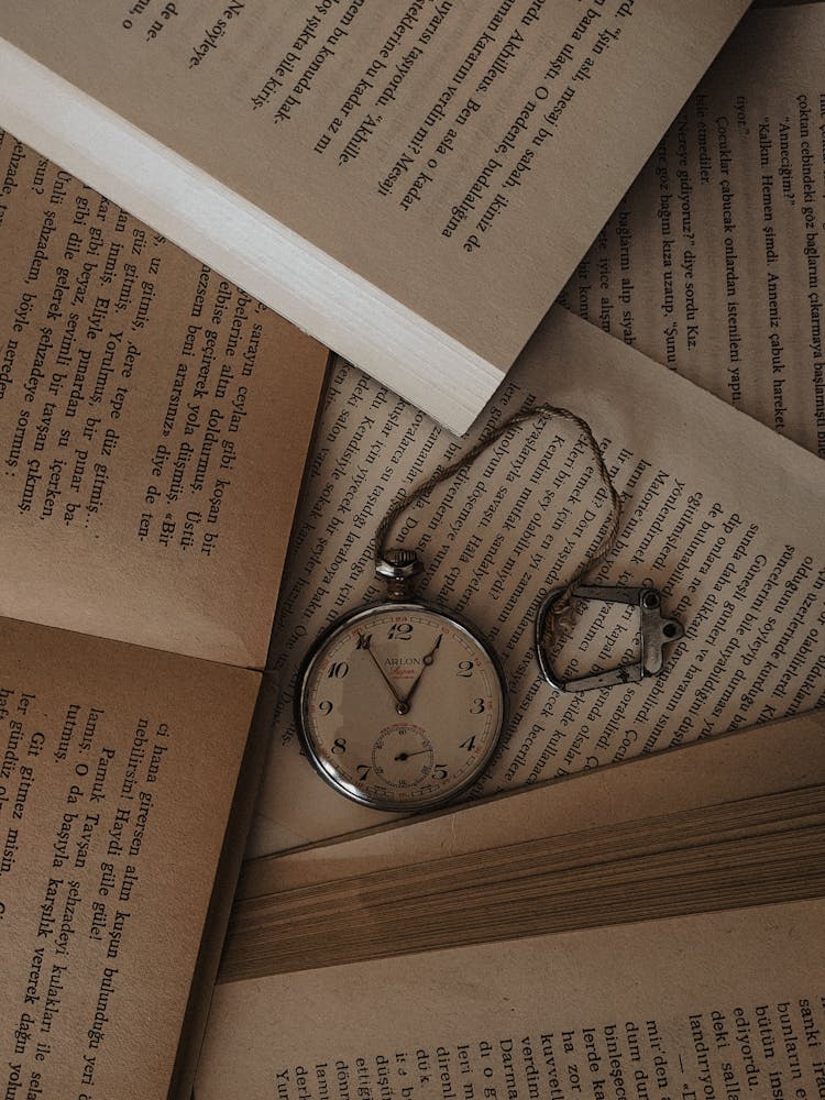 Silver Pocket Watch On Open Book