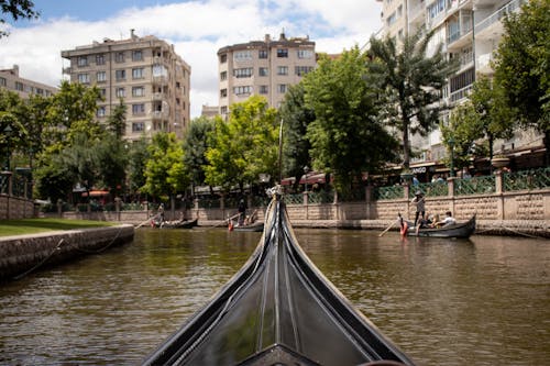 People Sailing in Gondolas on a River in City 