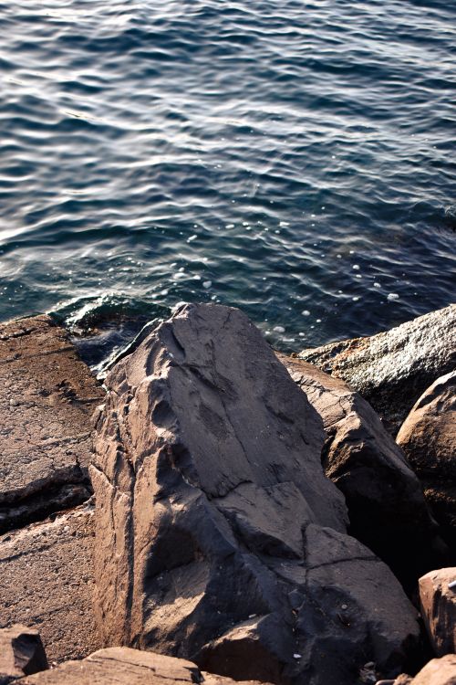 Free Serene view of rocky coastline with gentle sea waves creating a calming atmosphere. Stock Photo
