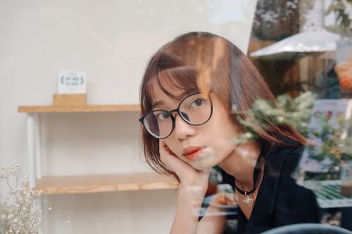 Free Reflective portrait of a woman with glasses at a cafe in Ho Chi Minh City. Stock Photo
