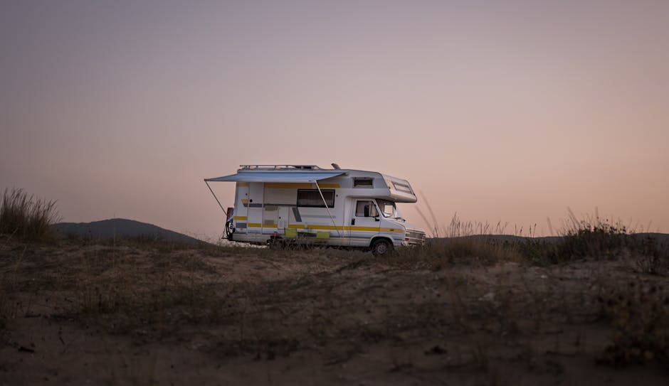 White and Blue Rv on Brown Field Under White Sky