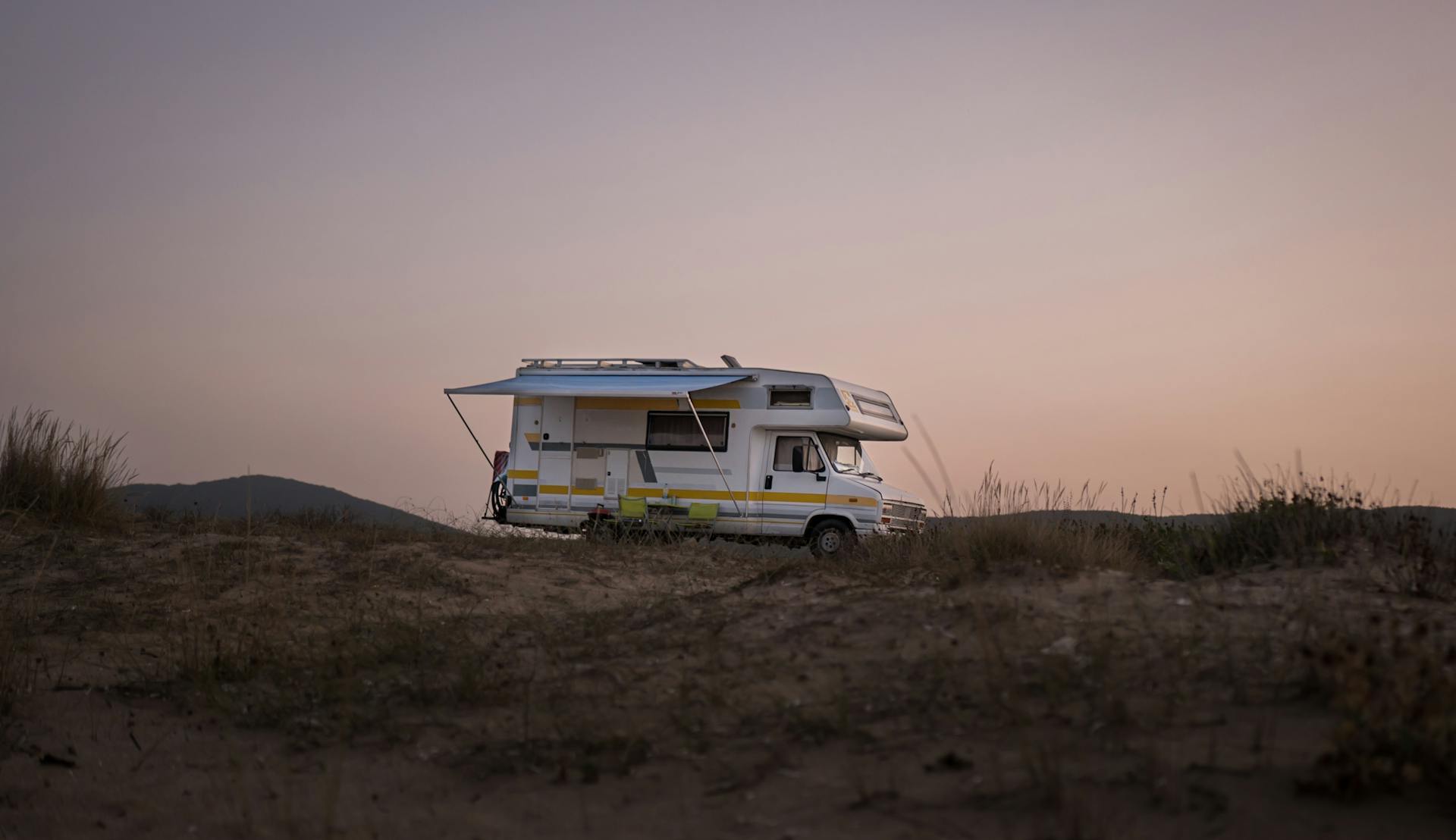 A serene view of an RV parked amidst nature during sunset, capturing a travel adventure.