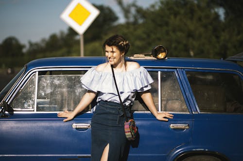 Free Woman Wearing White Off-shoulder Top While Touching Blue Car Stock Photo