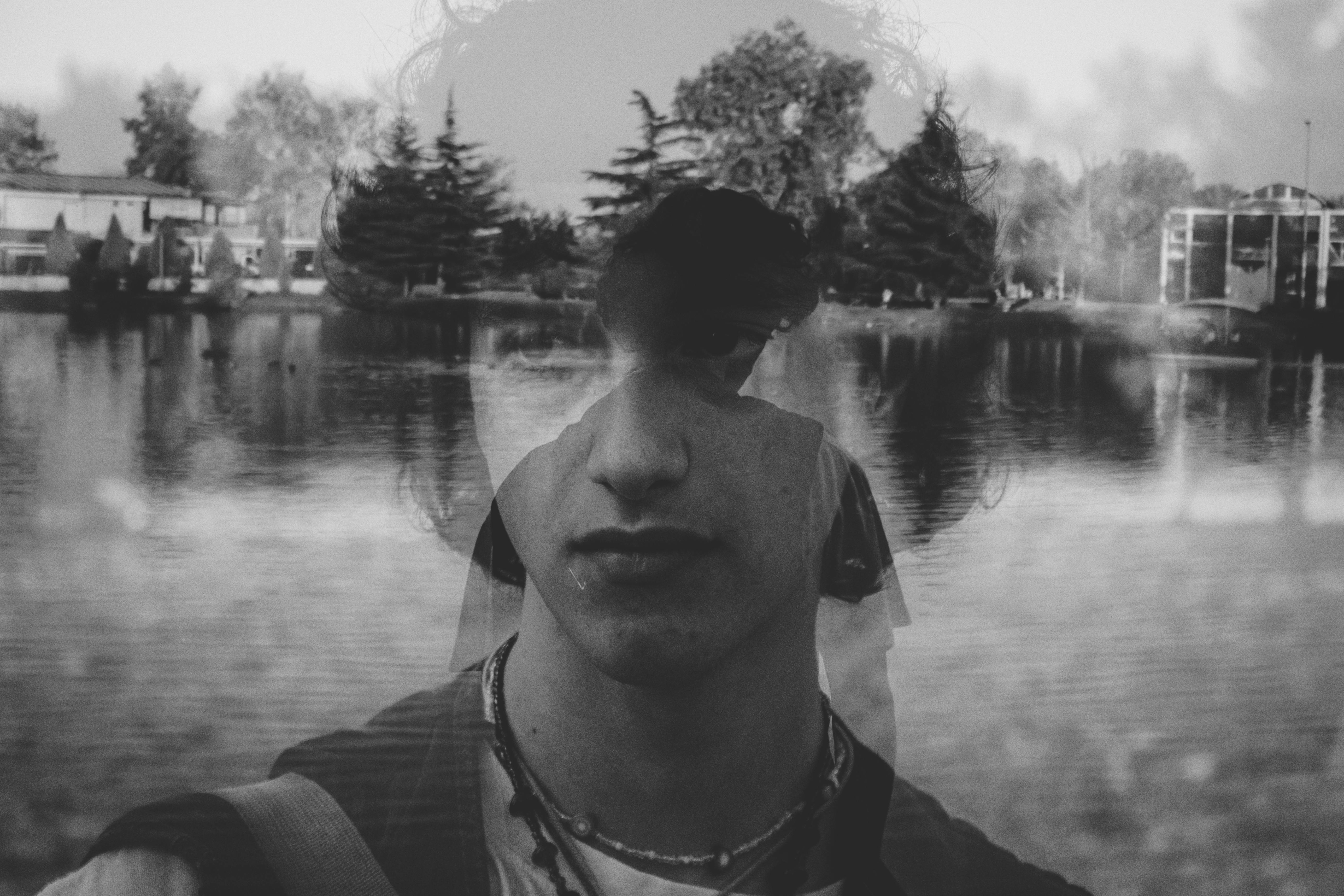 Artistic black and white double exposure of a young man with water reflection.
